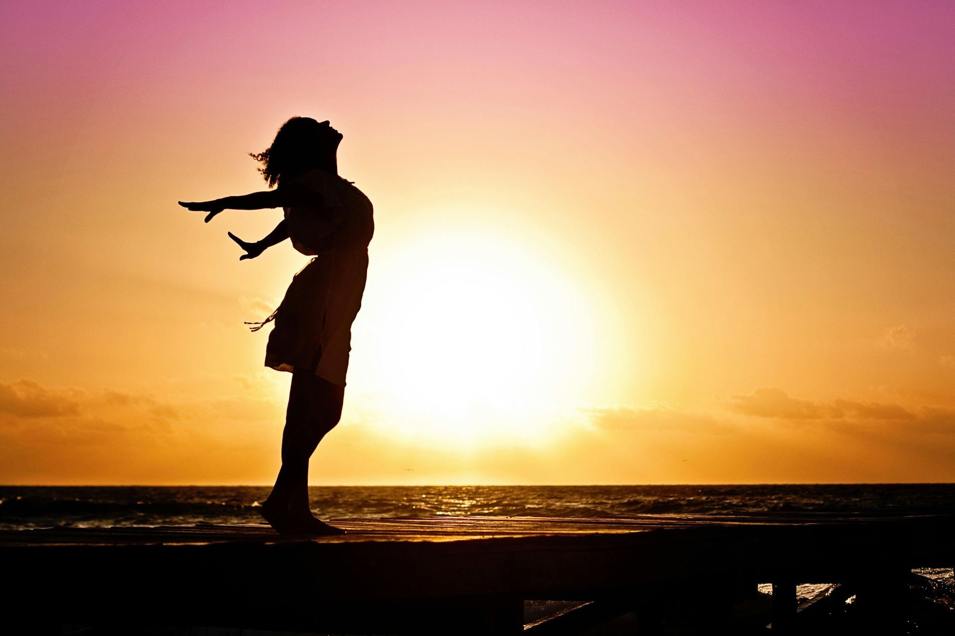 A woman greeting the sunrise, feeling calm and energised